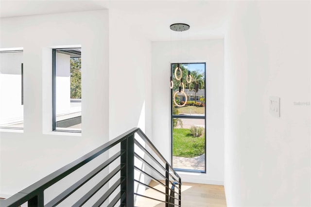 hall with light wood-style floors and an upstairs landing