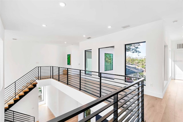 corridor with recessed lighting, visible vents, baseboards, an upstairs landing, and light wood-type flooring