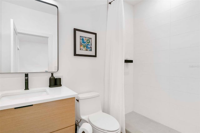 bathroom with tiled shower, vanity, and toilet