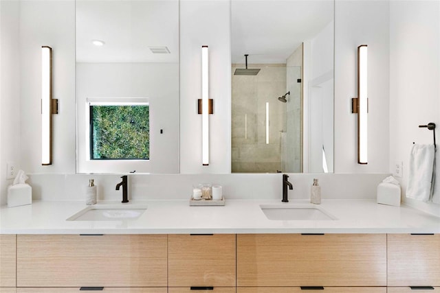 full bathroom with visible vents, a sink, a shower stall, and double vanity