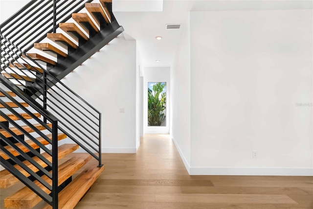 stairs with visible vents, baseboards, wood finished floors, and recessed lighting