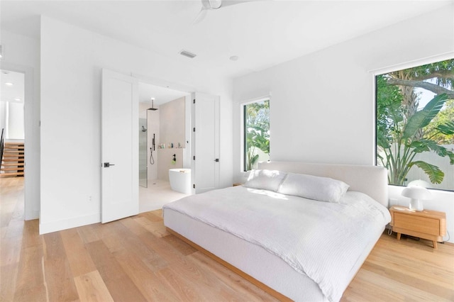 bedroom with light wood-style flooring, visible vents, and connected bathroom