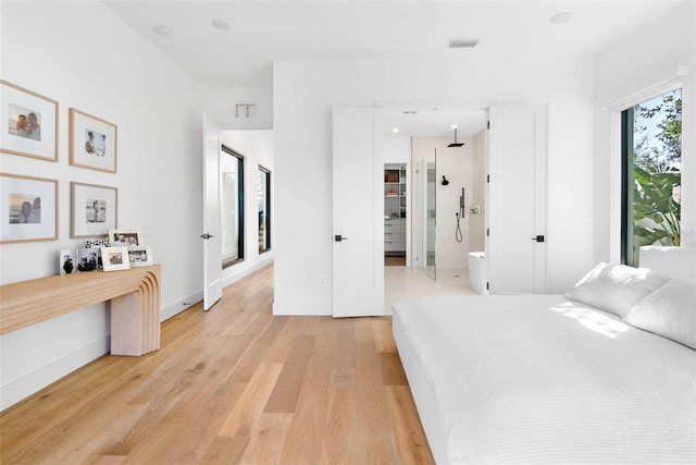 bedroom featuring light wood-style floors, visible vents, and baseboards