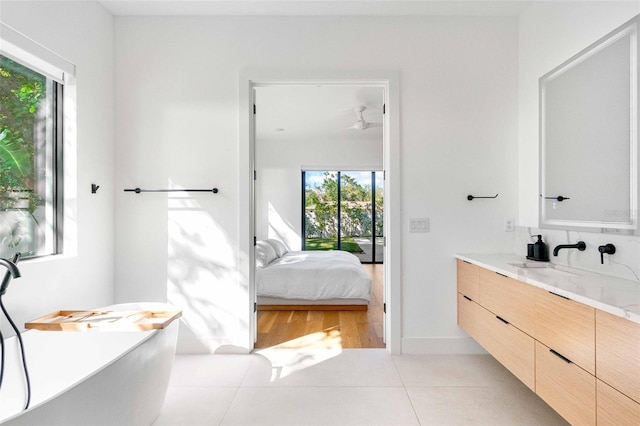 bathroom with a freestanding tub, connected bathroom, vanity, baseboards, and tile patterned floors