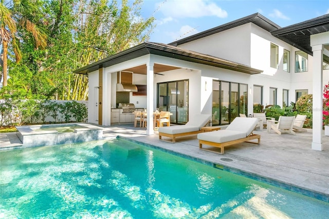 back of property with stucco siding, a pool with connected hot tub, a patio area, and area for grilling