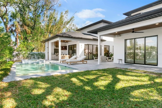 rear view of property featuring a patio, a hot tub, a lawn, and stucco siding