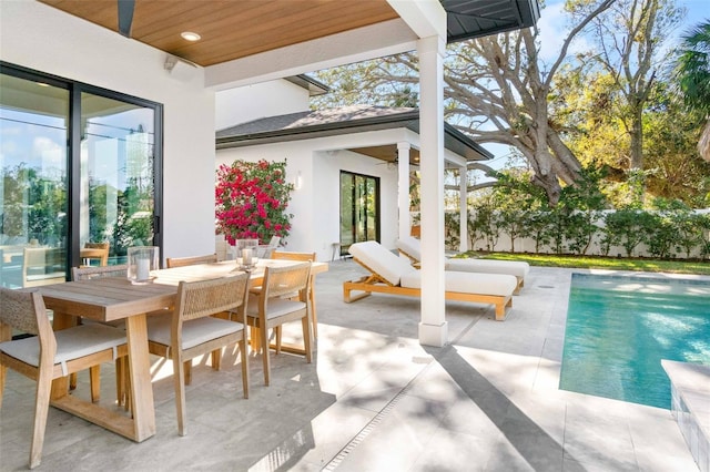 view of patio / terrace with outdoor dining space, fence, and an outdoor pool