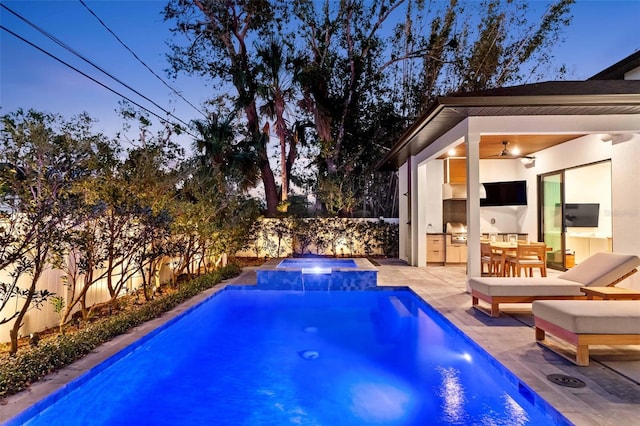 view of swimming pool with fence private yard, a pool with connected hot tub, a patio area, and an outdoor kitchen