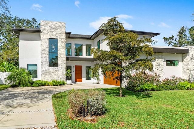 contemporary home with stone siding, a front yard, and stucco siding