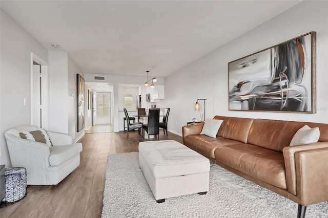 living area featuring visible vents, baseboards, and wood finished floors