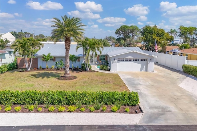 ranch-style home with a garage, a front yard, concrete driveway, and metal roof