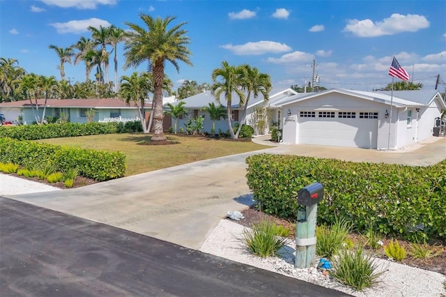 ranch-style house with a front lawn, concrete driveway, a garage, and stucco siding