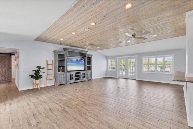 unfurnished living room with lofted ceiling, french doors, wood finished floors, and a barn door