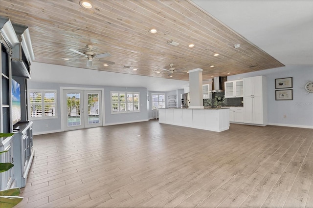 unfurnished living room with light wood finished floors, wood ceiling, a wealth of natural light, and french doors