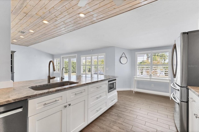 kitchen with stainless steel appliances, a sink, white cabinetry, french doors, and light stone countertops