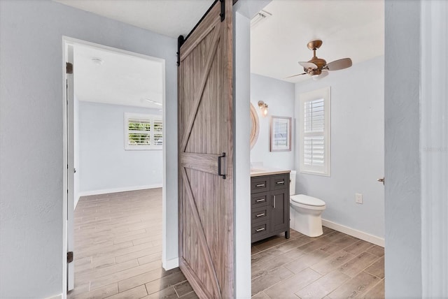 bathroom featuring baseboards, toilet, ceiling fan, wood tiled floor, and vanity