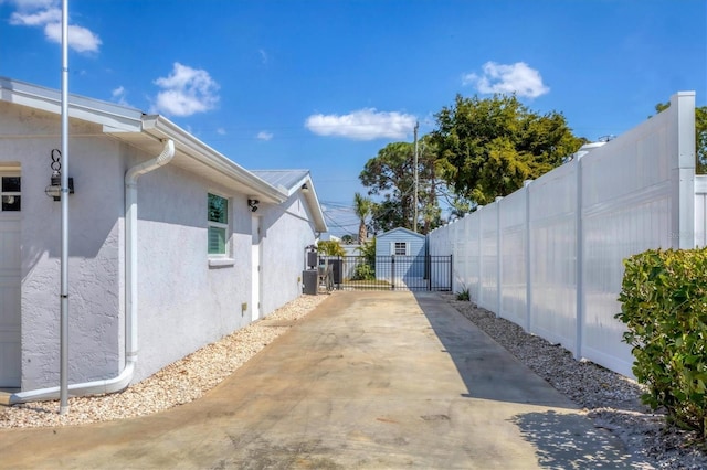 view of side of home featuring concrete driveway, fence, and stucco siding