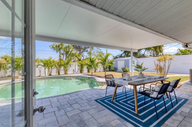 view of swimming pool with a fenced backyard, a storage unit, and a patio