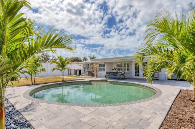 view of swimming pool featuring a patio area, fence, a fenced in pool, and french doors