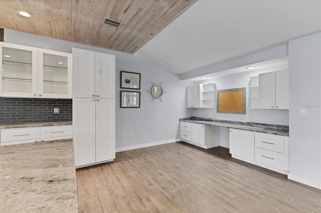 kitchen with light wood finished floors, open shelves, built in desk, and white cabinets