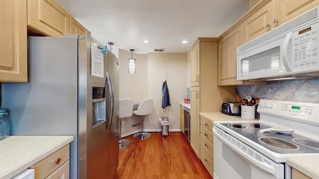 kitchen featuring white appliances, backsplash, light brown cabinets, and light countertops