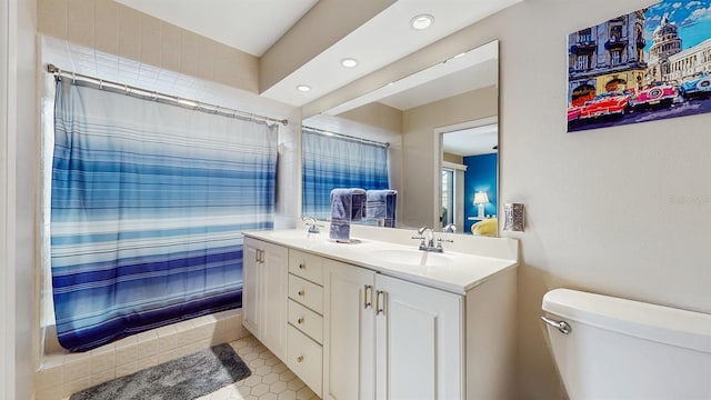 bathroom featuring double vanity, toilet, a shower with shower curtain, and a sink