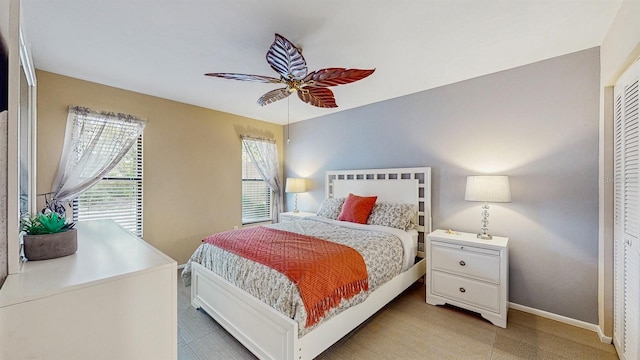 bedroom featuring light carpet, a ceiling fan, and baseboards