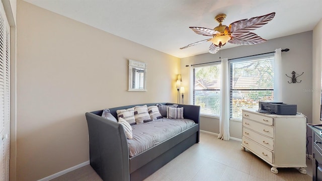 living area featuring a ceiling fan and baseboards