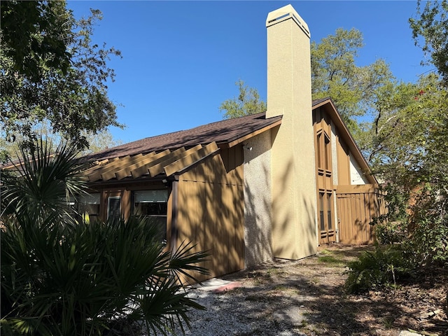 view of side of home with stucco siding and a chimney