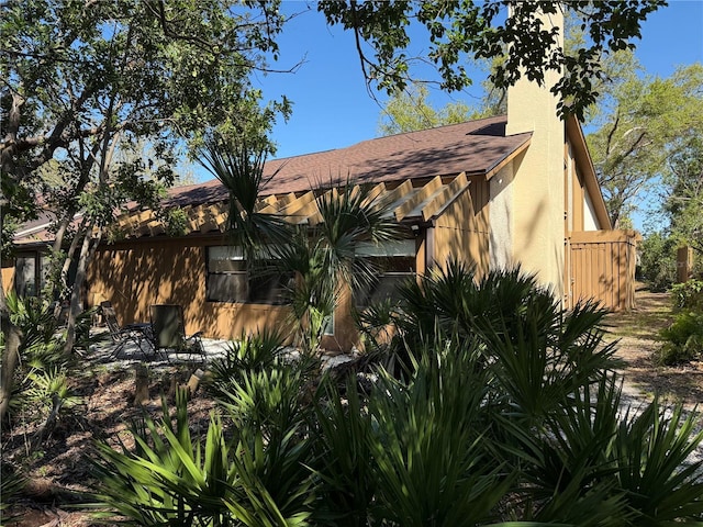 view of home's exterior with a chimney and a shingled roof