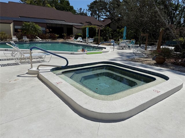 community pool with a community hot tub and a patio area