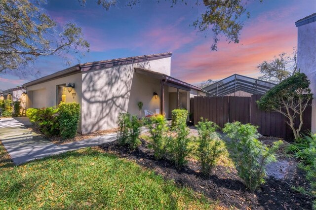 view of side of property featuring stucco siding, an attached garage, and fence