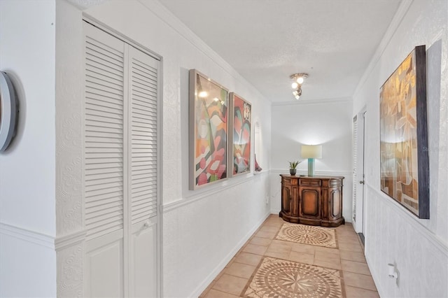 hallway with crown molding, light tile patterned flooring, and a textured ceiling