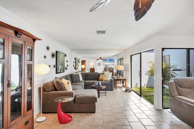 living area with visible vents, a textured ceiling, light tile patterned flooring, crown molding, and ceiling fan