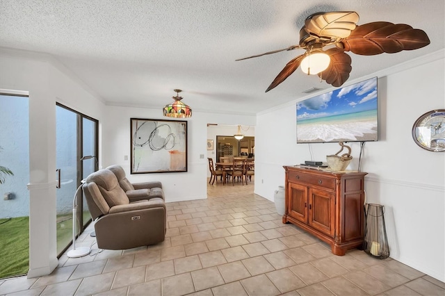 living area with ceiling fan, crown molding, visible vents, and a textured ceiling