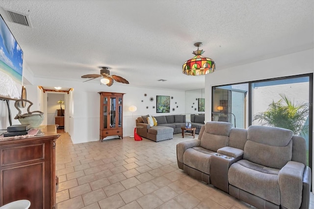 living area featuring light tile patterned floors, visible vents, a textured ceiling, and ceiling fan