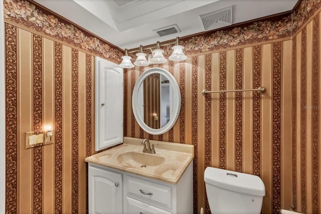 half bathroom featuring visible vents, toilet, wallpapered walls, and vanity