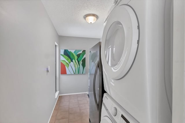 laundry room with stacked washer and dryer, a textured ceiling, light tile patterned flooring, baseboards, and laundry area