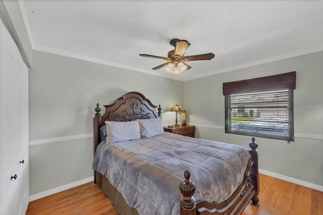 bedroom with a ceiling fan, wood finished floors, baseboards, ornamental molding, and a textured ceiling