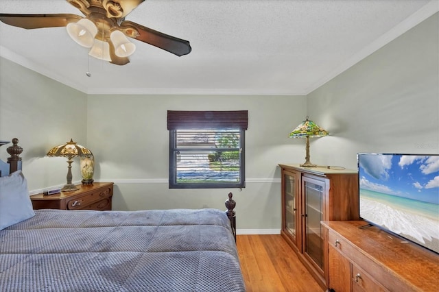 bedroom with crown molding, a ceiling fan, light wood-type flooring, and baseboards