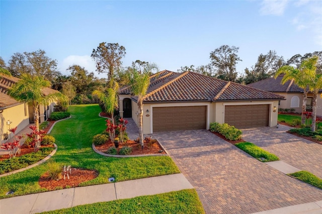 mediterranean / spanish house featuring a garage, a tile roof, decorative driveway, a front lawn, and stucco siding