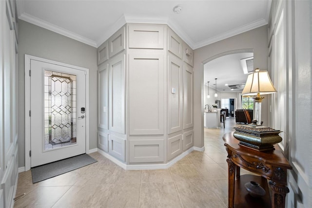 foyer entrance with arched walkways, crown molding, baseboards, and light tile patterned floors