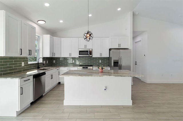 kitchen featuring stainless steel appliances, a center island, lofted ceiling, and light stone counters