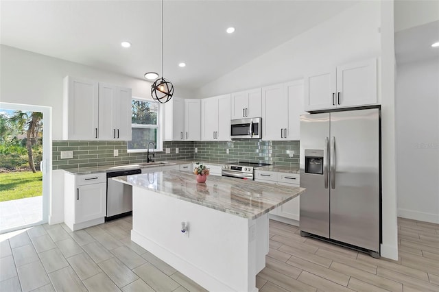 kitchen with tasteful backsplash, light stone counters, vaulted ceiling, stainless steel appliances, and white cabinetry