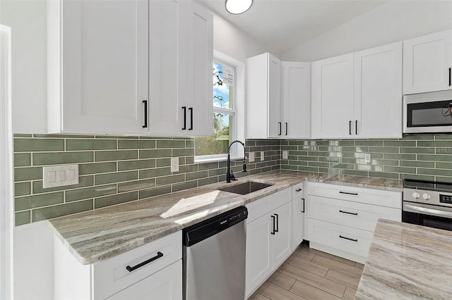 kitchen with light stone countertops, appliances with stainless steel finishes, decorative backsplash, and a sink