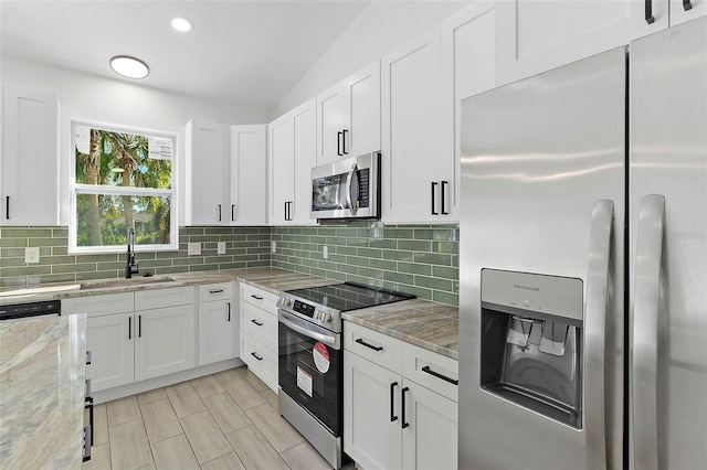 kitchen featuring appliances with stainless steel finishes, white cabinets, a sink, and decorative backsplash