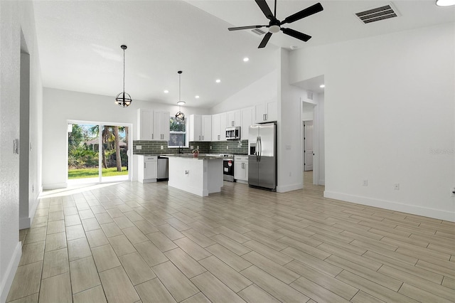 kitchen with ceiling fan with notable chandelier, stainless steel appliances, visible vents, open floor plan, and decorative backsplash