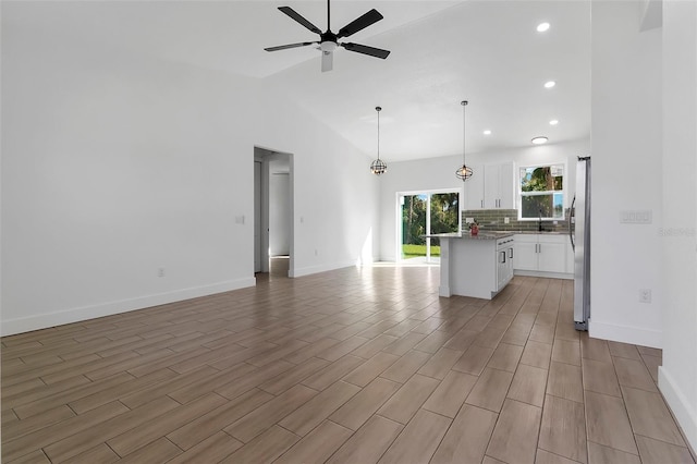 kitchen featuring backsplash, a ceiling fan, freestanding refrigerator, open floor plan, and white cabinets