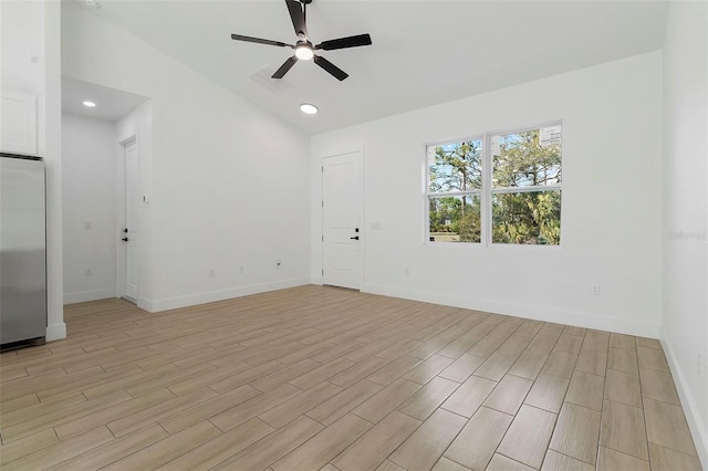 empty room featuring a ceiling fan, light wood-style floors, vaulted ceiling, visible vents, and baseboards