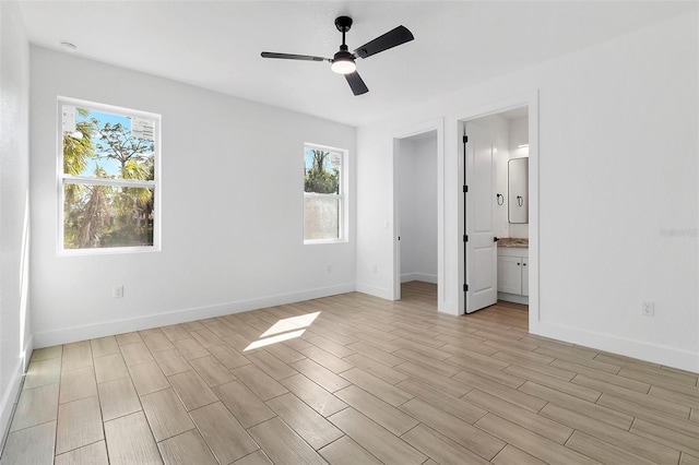 unfurnished bedroom featuring light wood-style flooring, baseboards, a ceiling fan, and ensuite bathroom